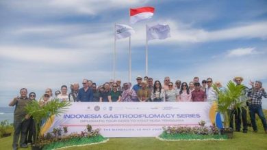 Diplomatic Tour Goes to West Nusa Tenggara." Tiga tiang bendera berdiri di belakang mereka, termasuk satu bendera Indonesia. Acara berlangsung di The Mandalika pada tanggal 8-10 Mei 2023. Lokasinya tampak seperti area terbuka dengan pemandangan laut. (Iam/Ist)