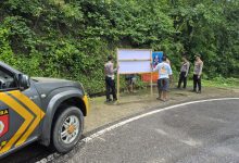 Anggota Kepolisian Polres Kabupaten Bima, tengah memasang Banner Himbauan dijalan rawan kecelakaan. (Fen/Ist)