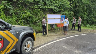 Anggota Kepolisian Polres Kabupaten Bima, tengah memasang Banner Himbauan dijalan rawan kecelakaan. (Fen/Ist)