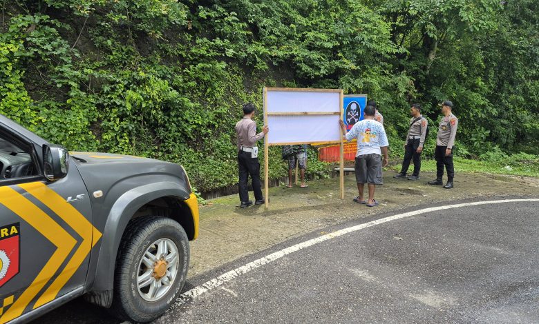Anggota Kepolisian Polres Kabupaten Bima, tengah memasang Banner Himbauan dijalan rawan kecelakaan. (Fen/Ist)